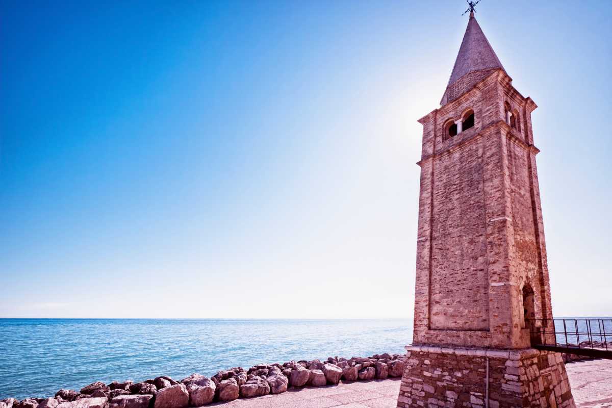 Scorcio sul centro storico di Caorle durante una festa serale, bandiere colorate e gente in festa tra le calli illuminate